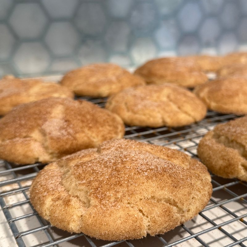 A finished batch of snickerdoodles cooling on a wire rack